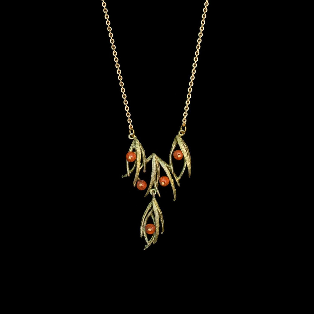 A green-toned leafy pendant necklace with small orange-red bead accents, shown against a solid black background.