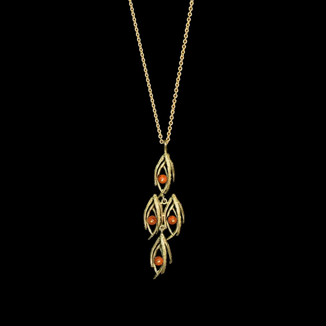 A green pendant necklace featuring three vertical leaf-like motifs with small orange gemstone accents, suspended from a delicate gold chain against a solid black background.