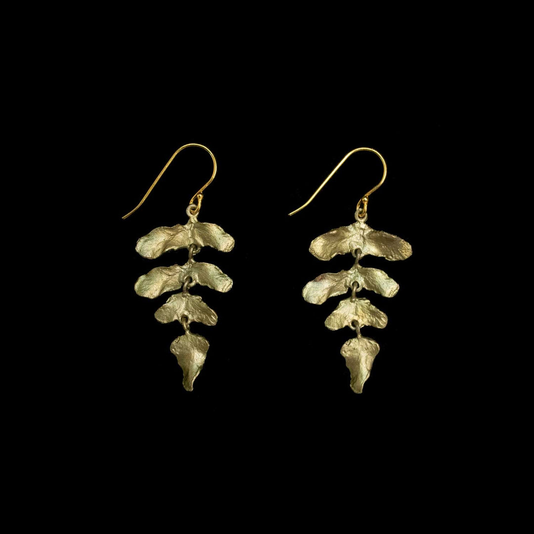 A pair of green dangle earrings with textured, leaf-like organic shapes, shown against a solid black background.