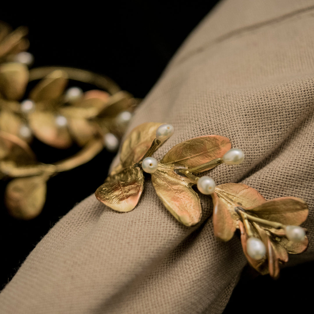 Gold leaf and pearl napkin rings on a beige fabric background