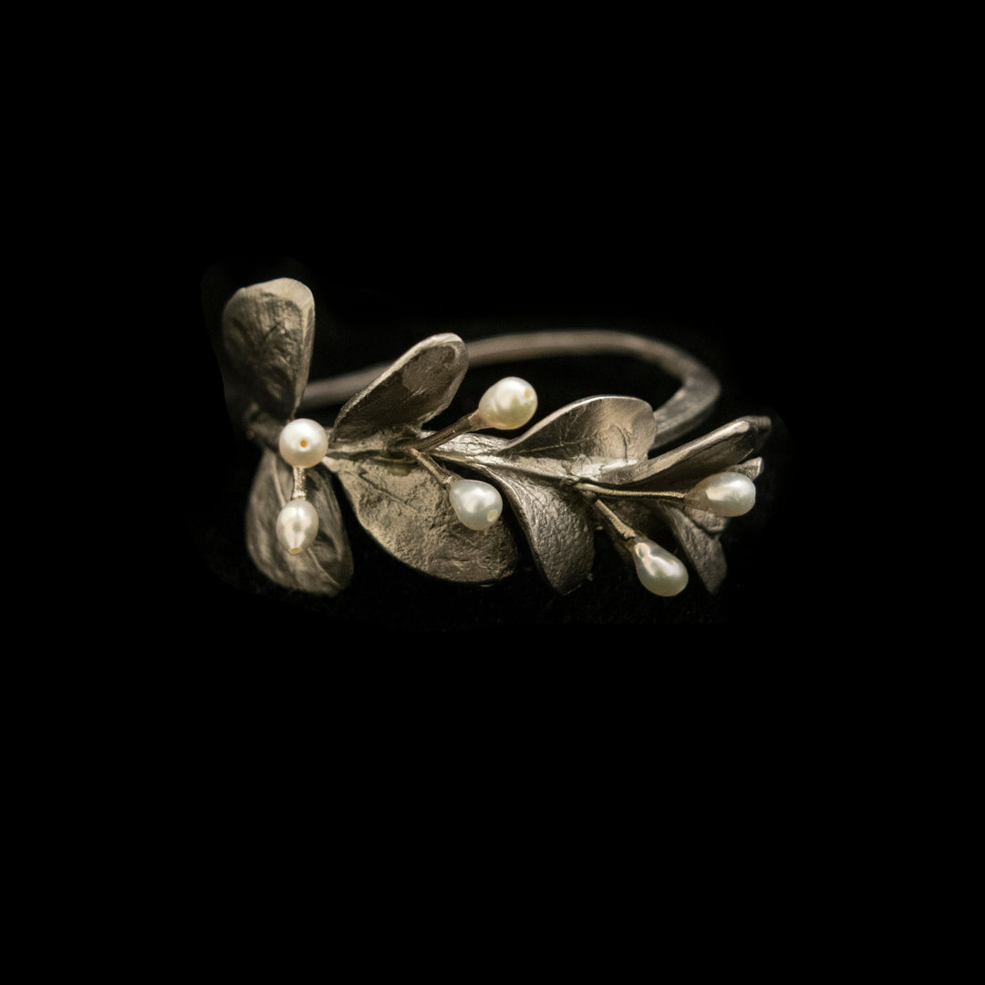 Silver leaf-shaped napkin ring with pearls on a black background