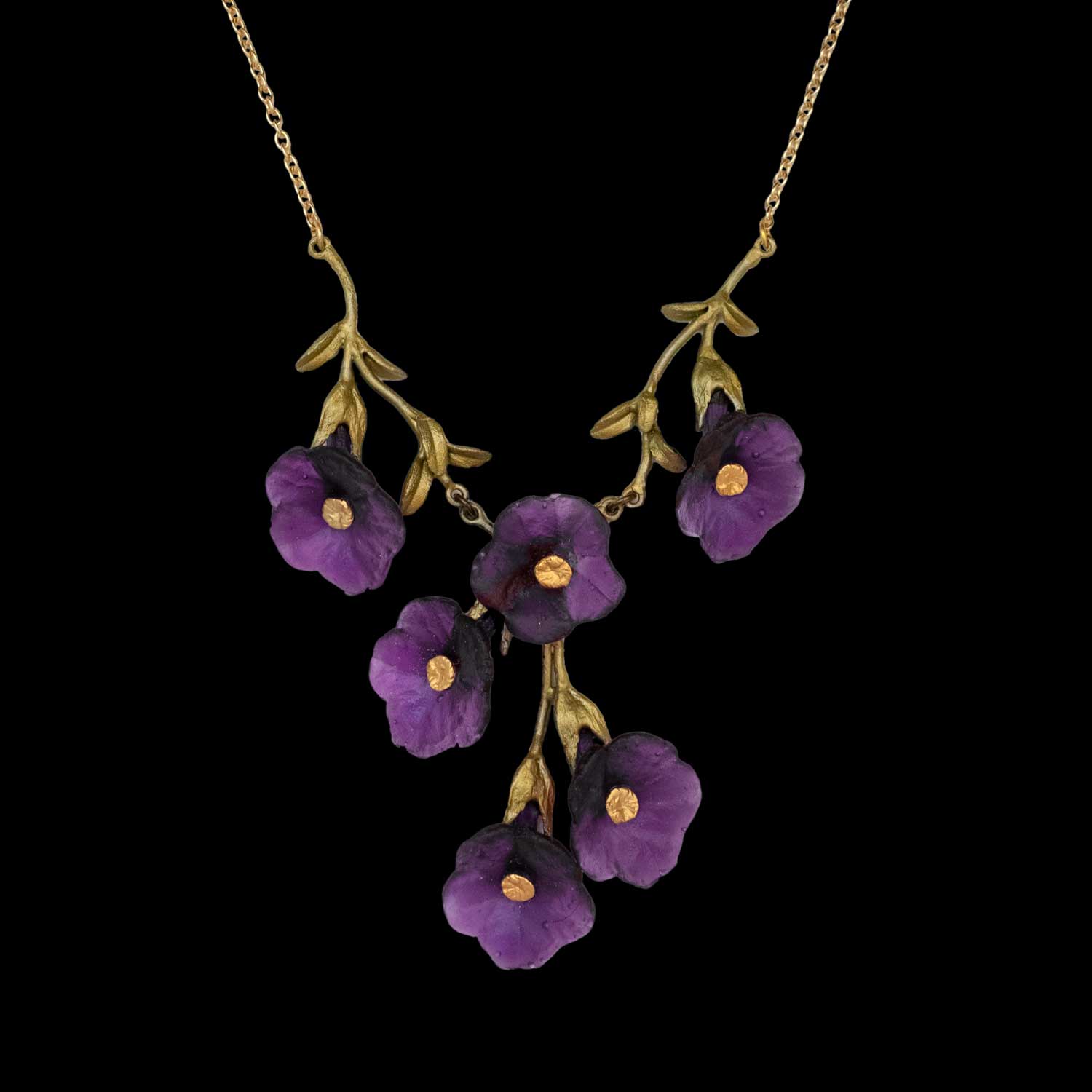A nature-inspired necklace, this gold piece features five purple flower-shaped pendants and green leaf accents, arranged symmetrically against a black background—a stunning example of handcrafted jewelry.
