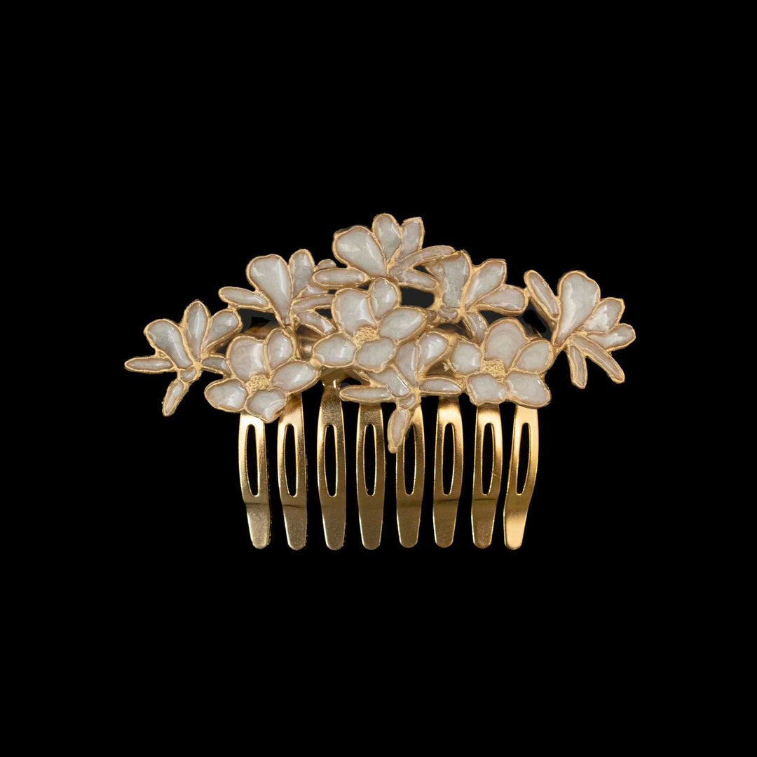 A gold hair comb featuring a cluster of white flowers with gold borders, set against a solid black background.