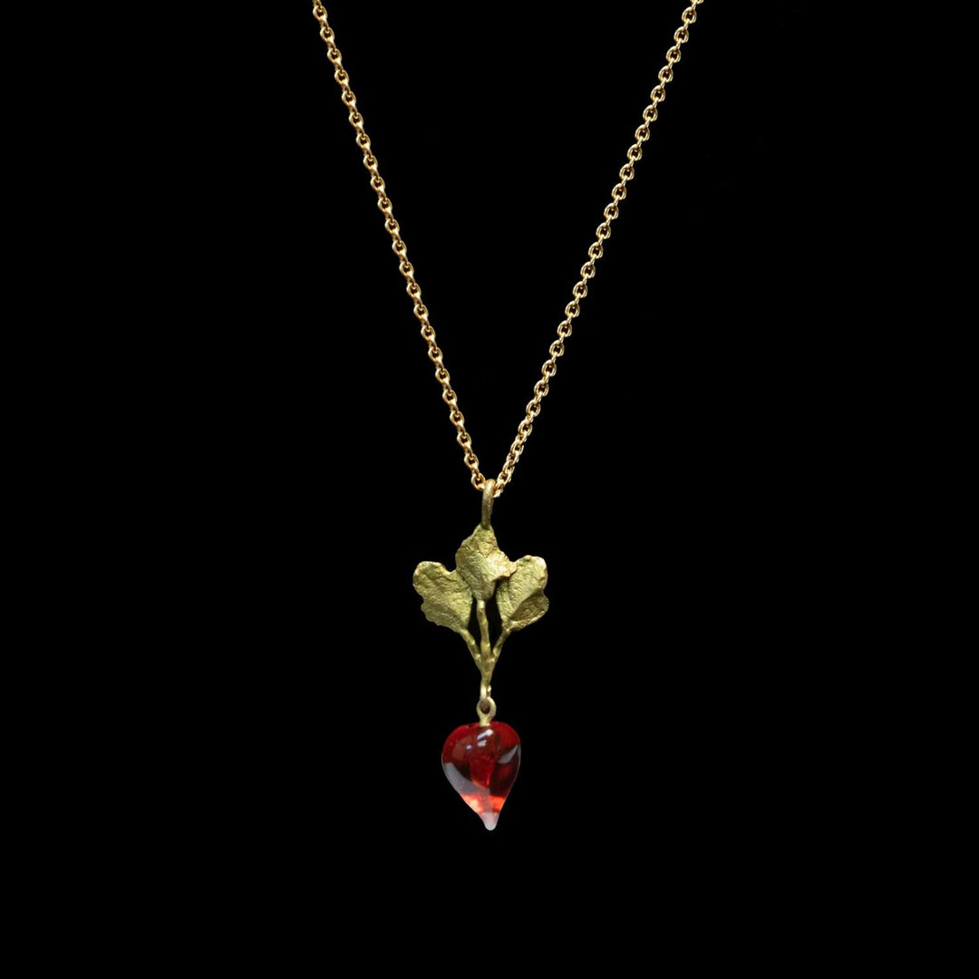 A gold necklace featuring a leaf pendant with a dangling red glass radish, shown against a solid black background.