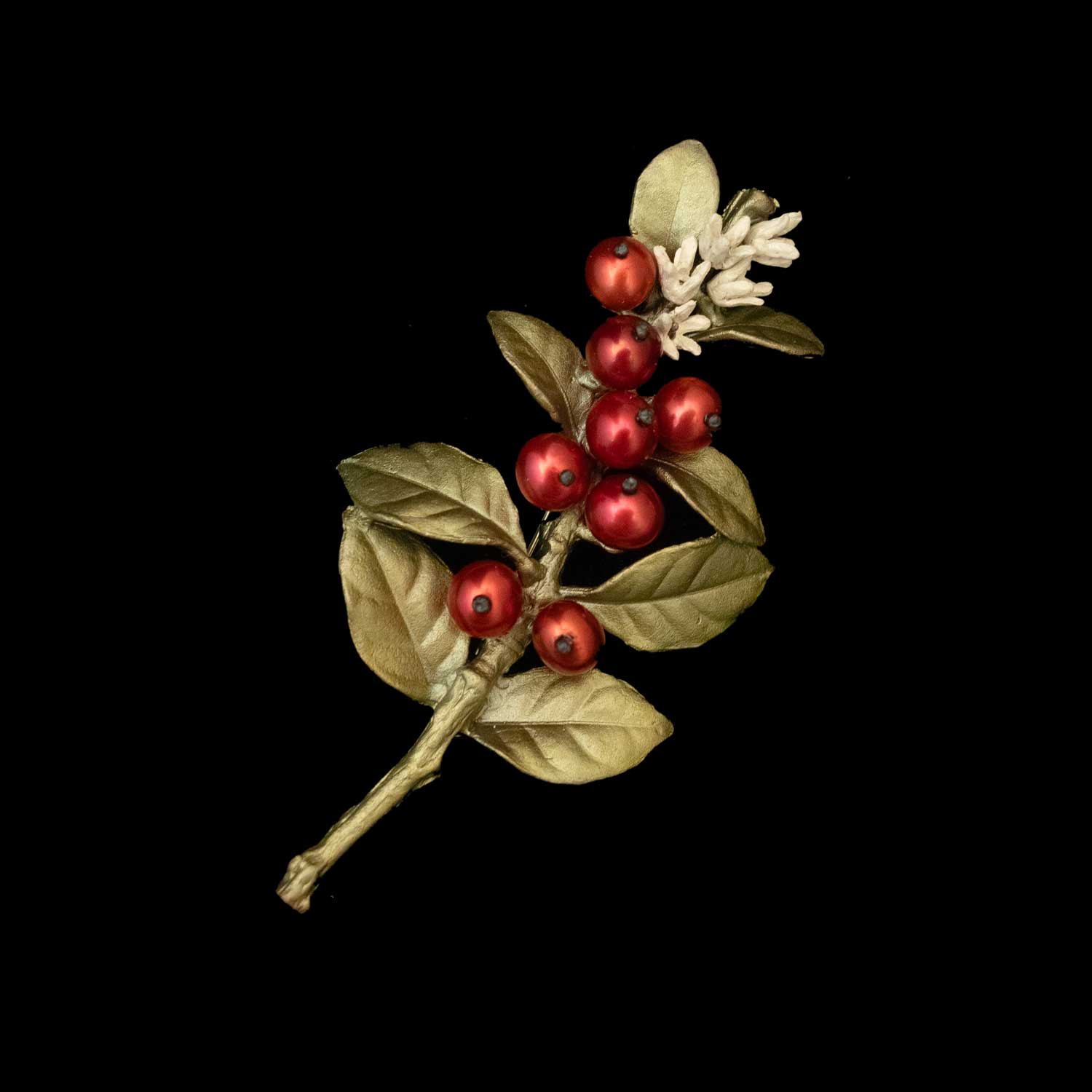 The Unroasted Coffee Bean Brooch, styled with red berries, green leaves, and white flowers—evoking a bronze leaf brooch—appears against a solid black background.